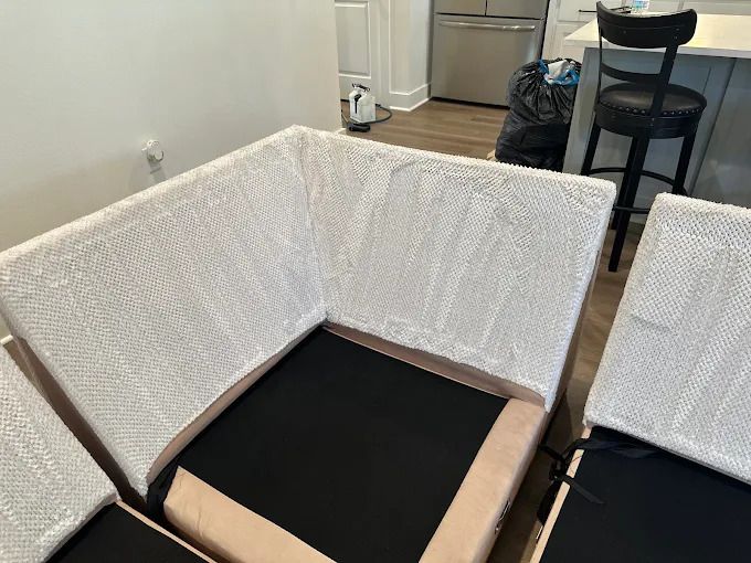 Sectional sofa with white textured fabric and black cushions in a room.