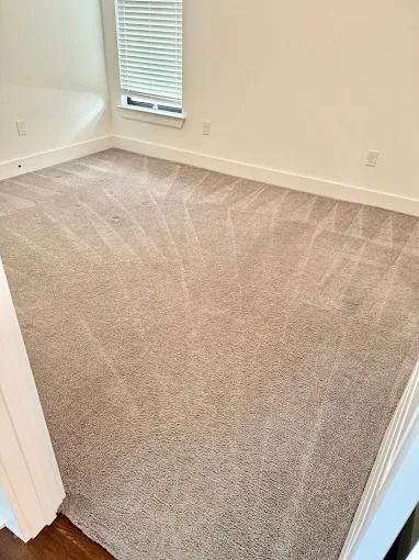 Empty room with tan carpet, white walls, and a small window with blinds.