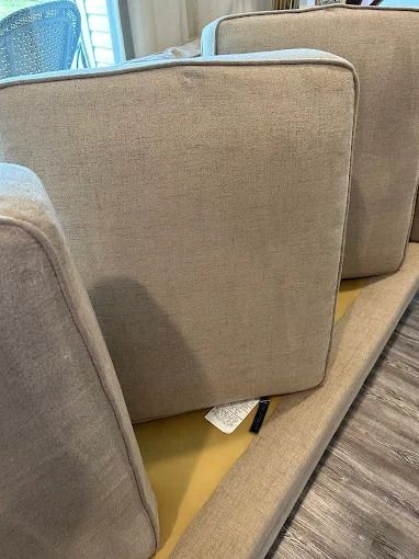 Close-up of tan couch cushions stacked, resting on a yellow surface, indoors.