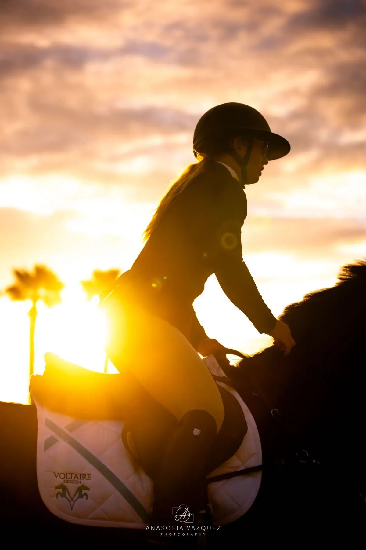 Silhouette of a person riding a horse at sunset. The rider is wearing a helmet, and the sun is shining brightly.
