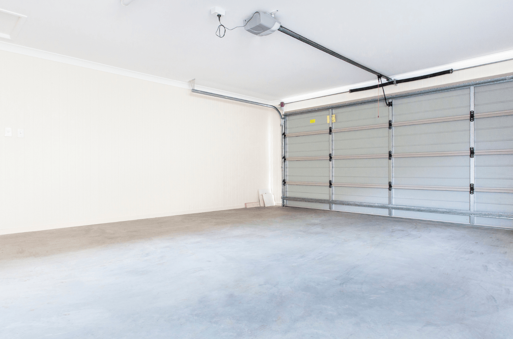 An empty garage with a garage door open and a garage door opener.