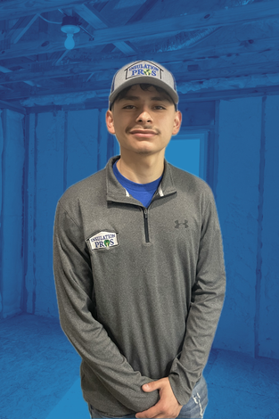 A man wearing a hat and a polo shirt is standing in an empty room.