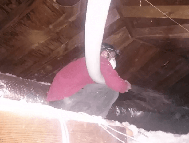 A man wearing a mask is working in an attic.