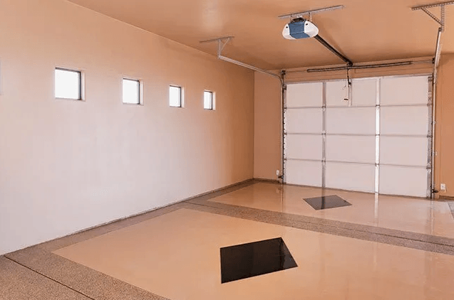 An empty garage with a garage door open and a hole in the floor.