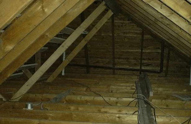 An attic with a lot of wooden beams and pipes