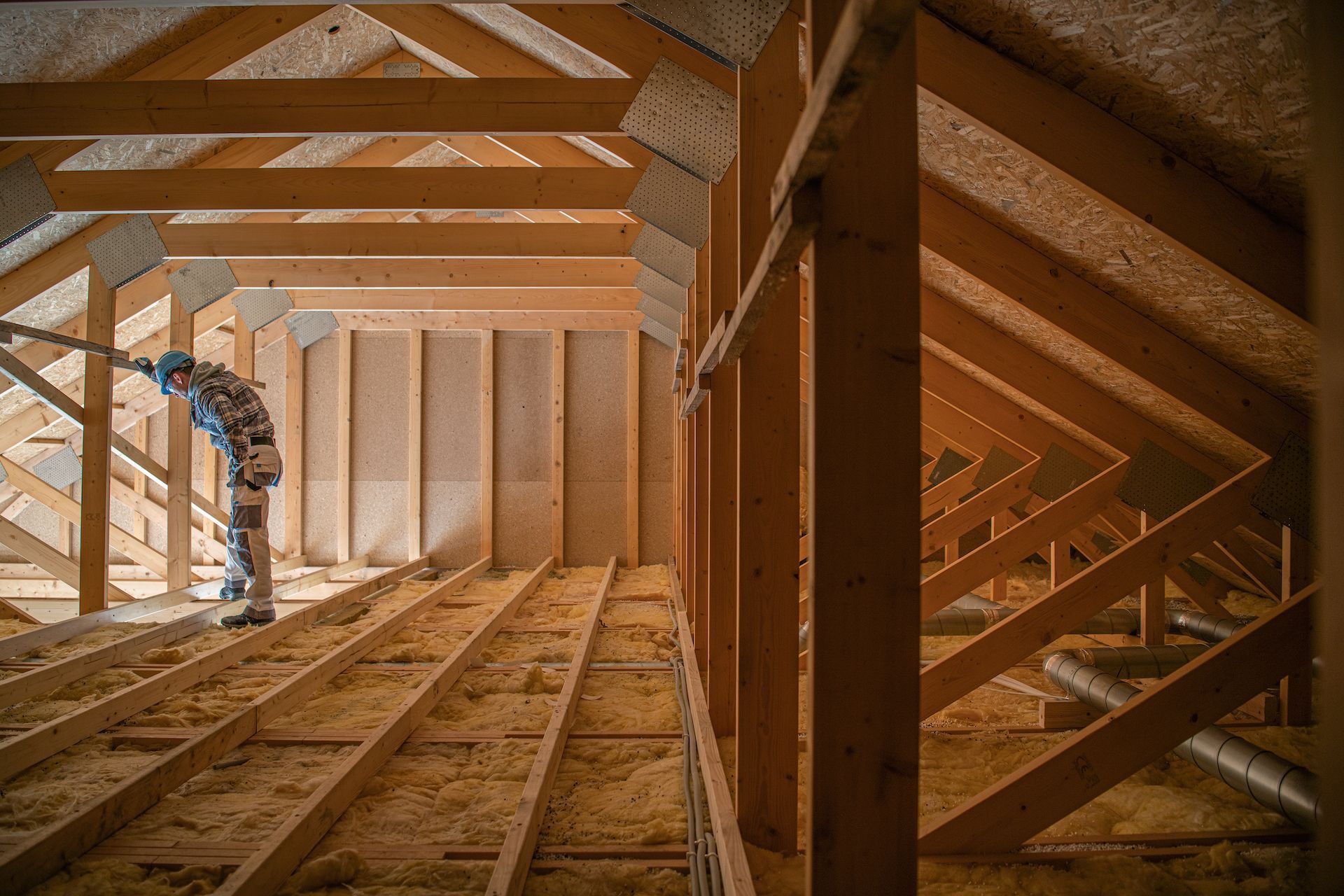 A man is standing in the attic of a house under construction.