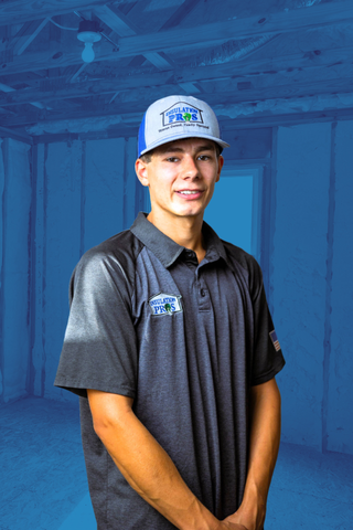 A young man wearing a hat and a polo shirt is standing in a room.