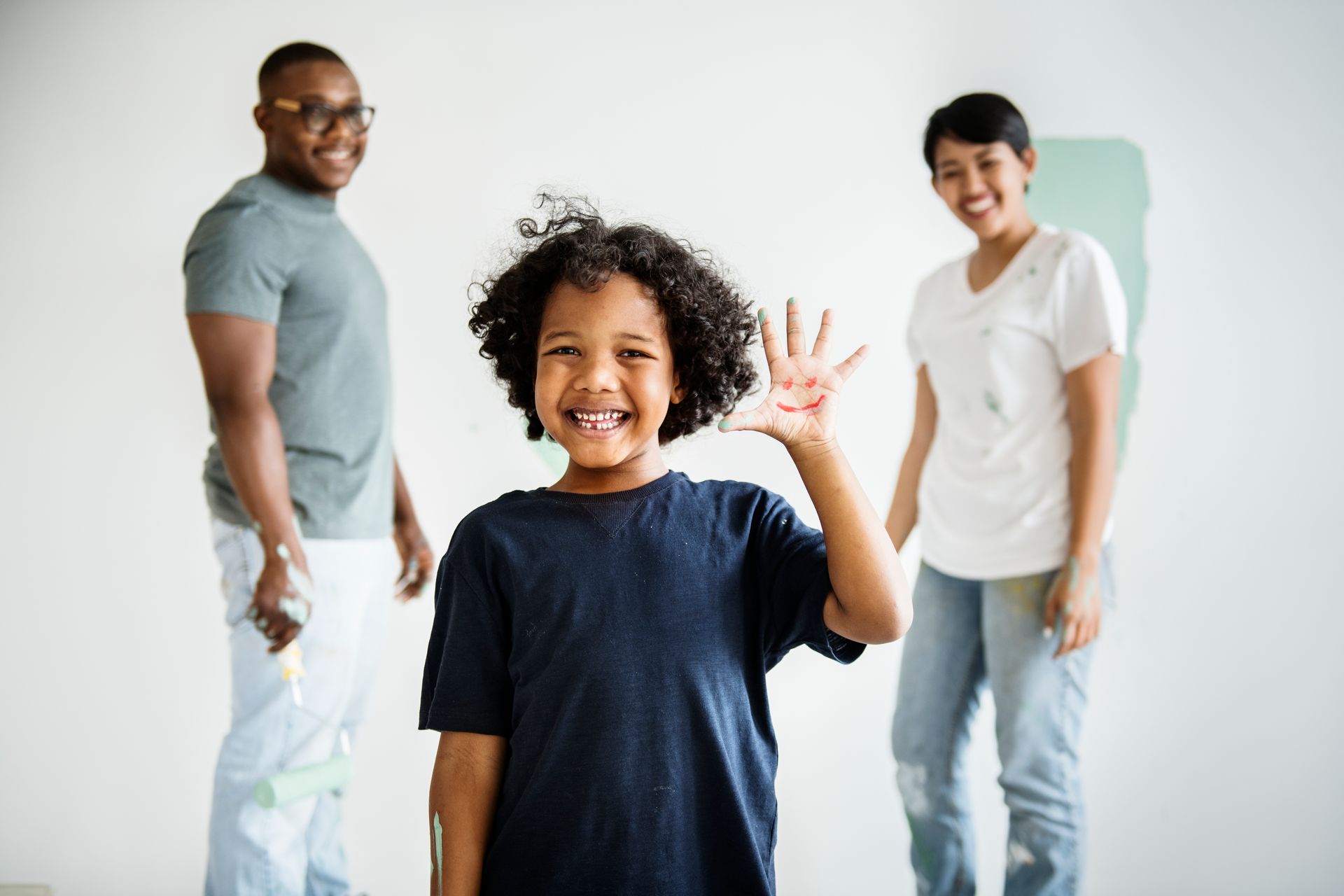 A young boy is waving at the camera while standing next to a man and woman.