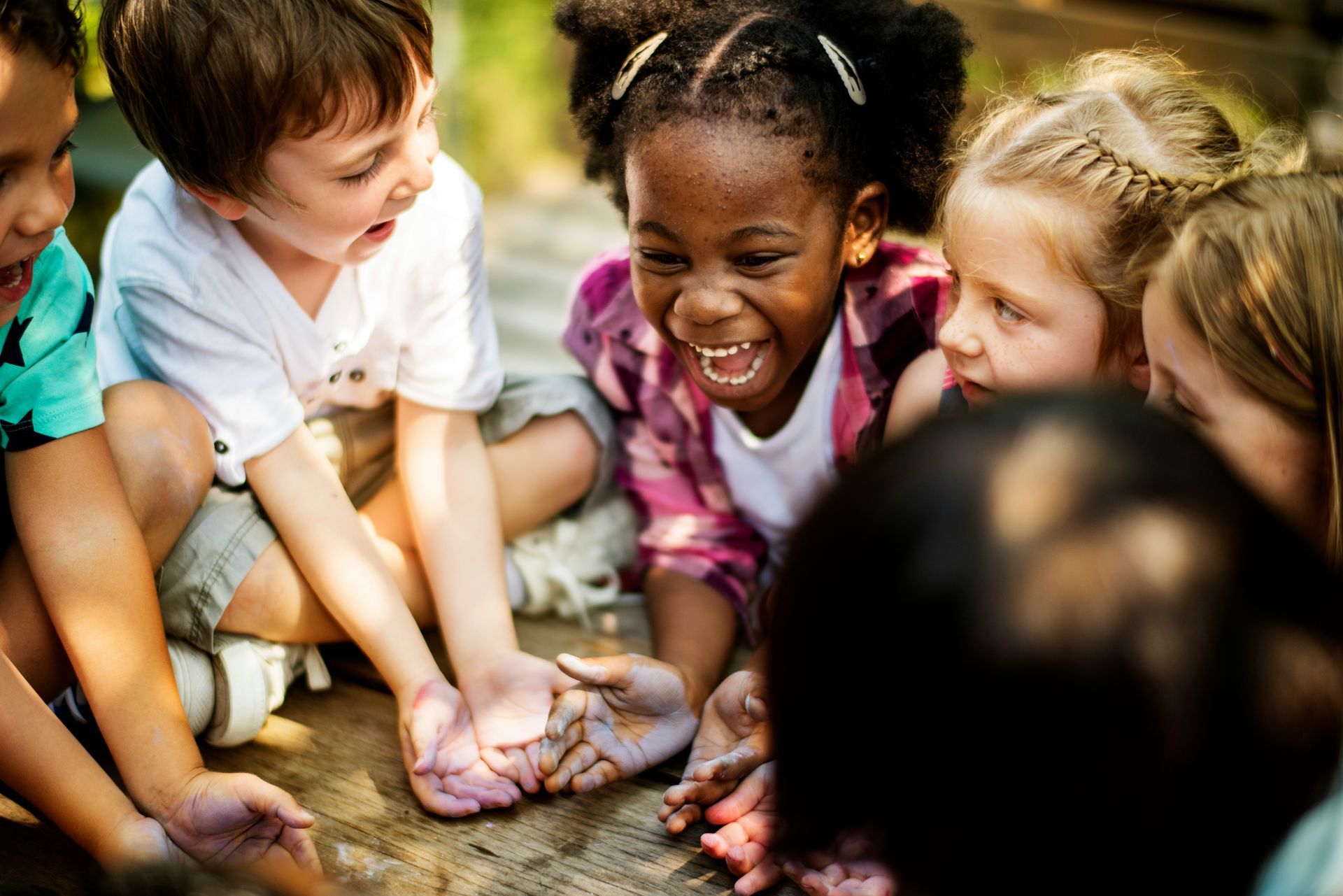 A group of children are sitting on the ground playing with clay.