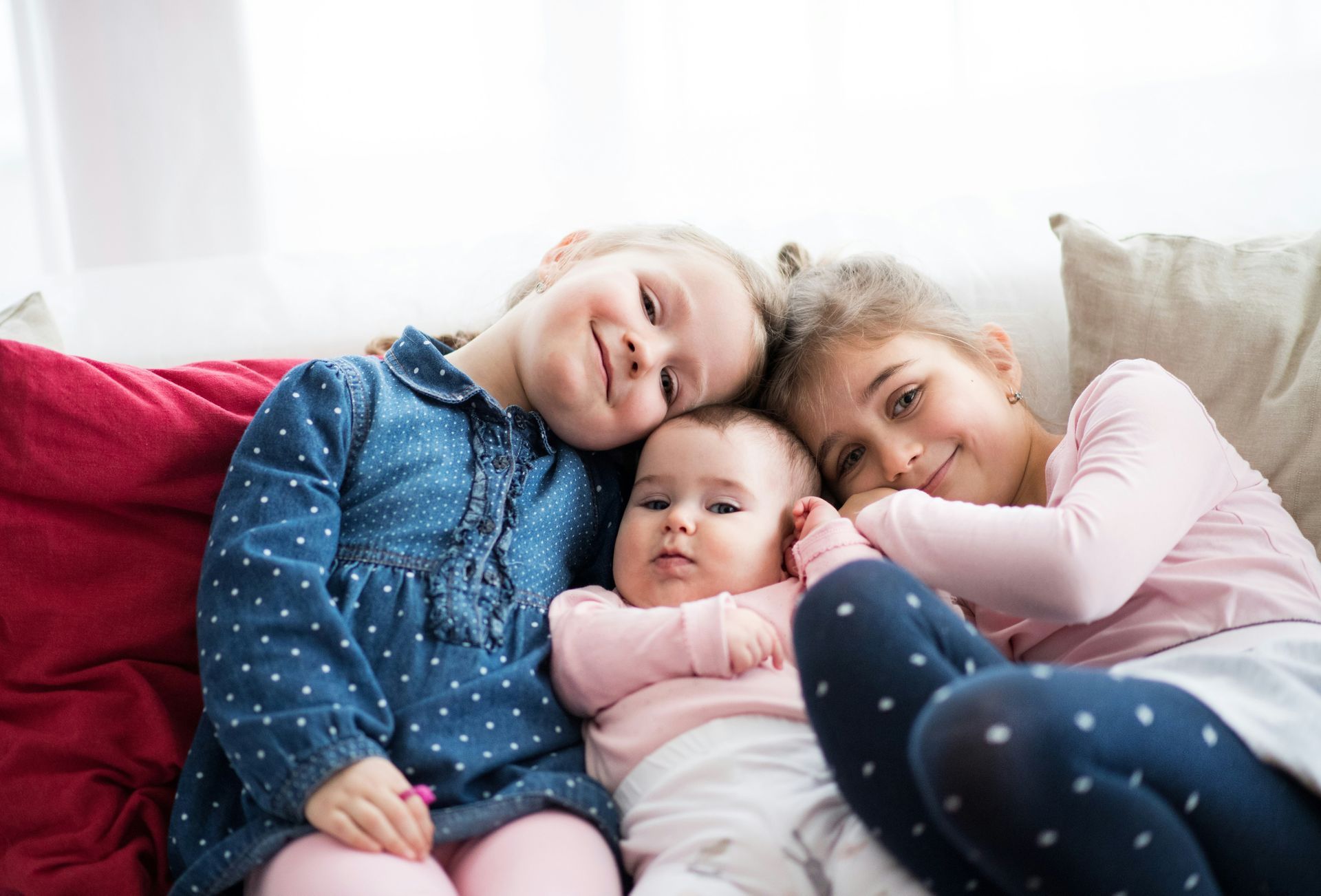 Three little girls are sitting on a couch with a baby.