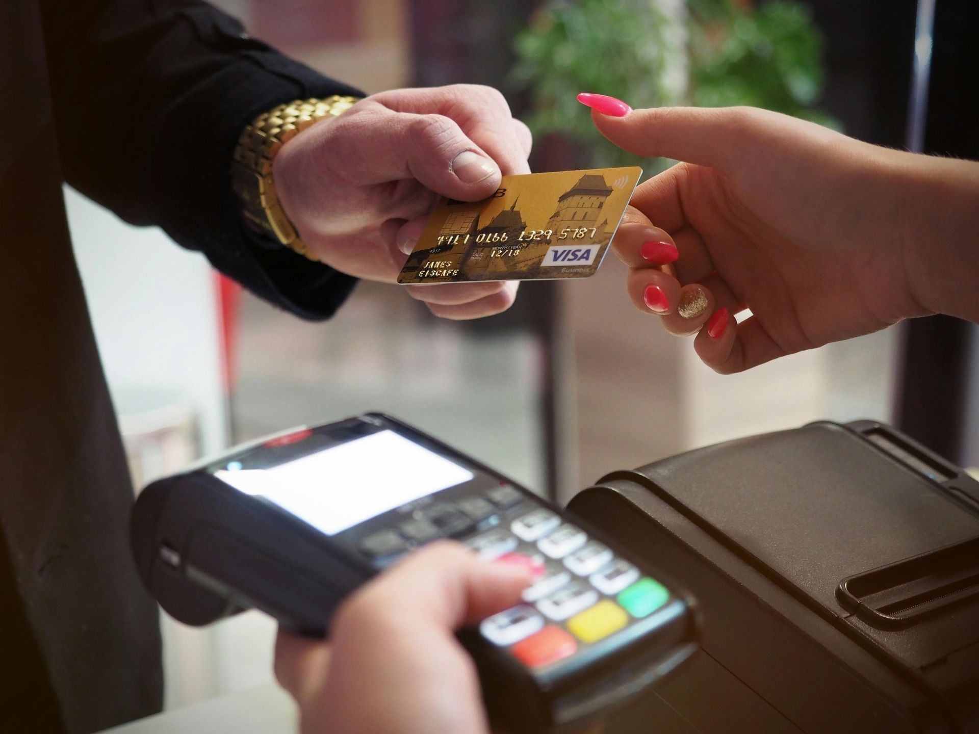 Person handing credit card to another near a payment terminal.