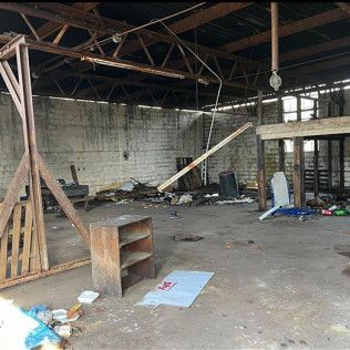 The inside of an abandoned building with a lot of trash on the floor.