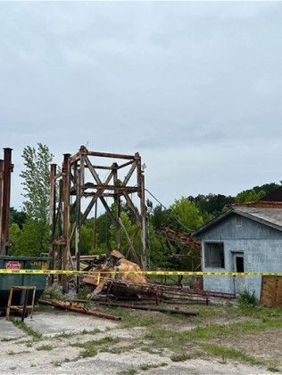 A building with a yellow tape surrounding it is being demolished.