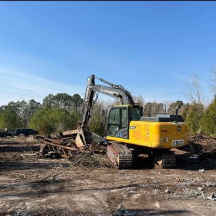 A yellow excavator is sitting in the middle of a dirt field.