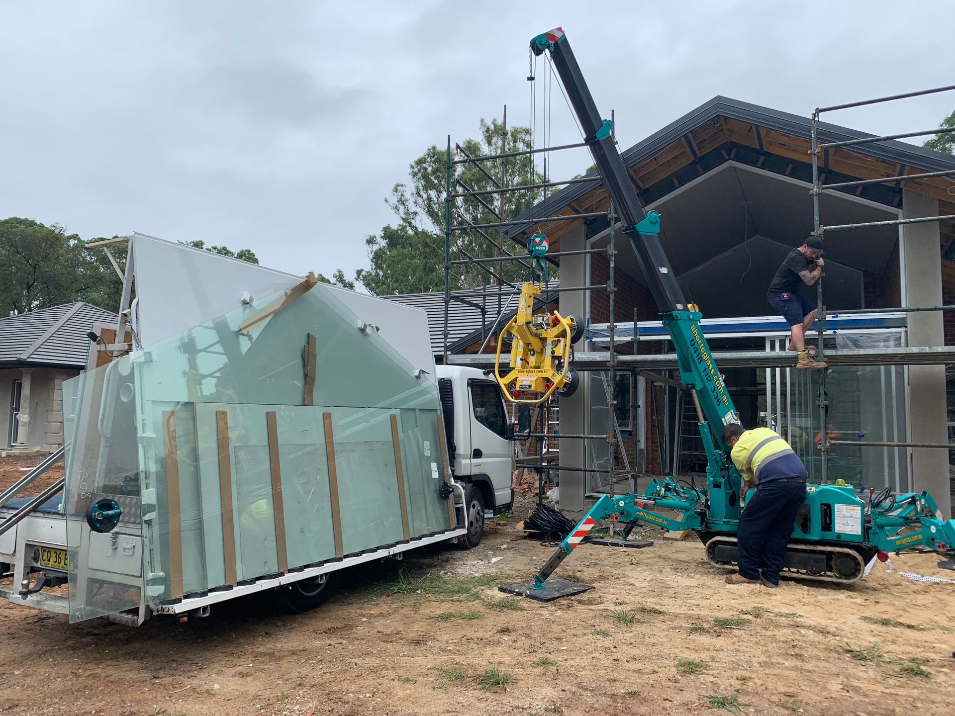 Crane Lifting Large Glass Panel at Construction Site — Central Coast Glass & Glazing In Umina Beach, NSW