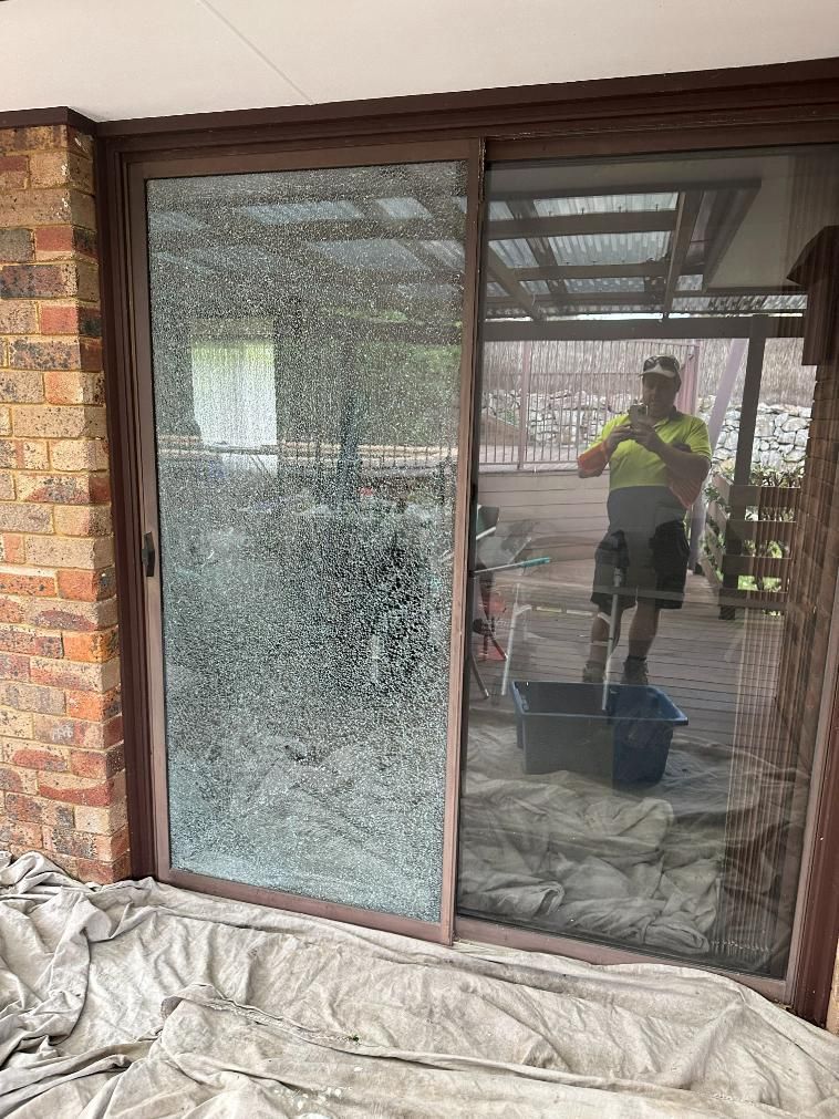 A Man Is Standing In Front Of A Sliding Glass Door — Central Coast Glass & Glazing In Terrigal, NSW