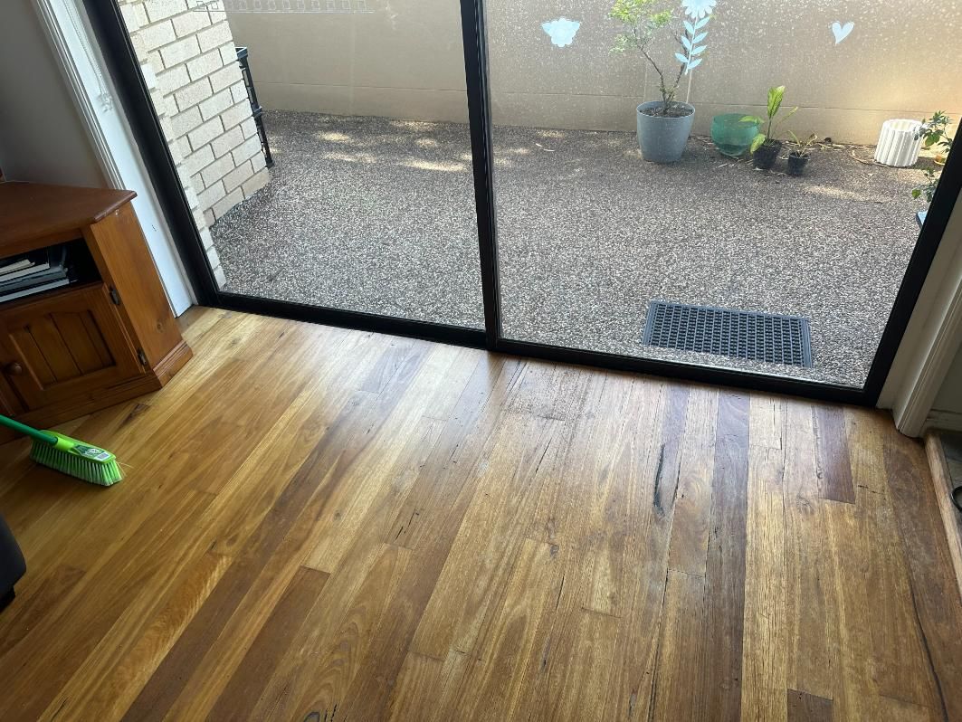 A Living Room With Hardwood Floors And A Sliding Glass Door — Central Coast Glass & Glazing In Woy Woy, NSW