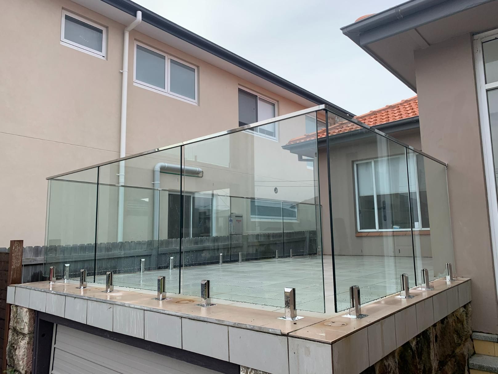 A Balcony With A Glass Railing Is In Front Of A House — Central Coast Glass & Glazing In Umina Beach, NSW