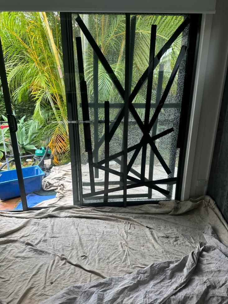 A Sliding Glass Door Is Taped To The Wall In A Room — Central Coast Glass & Glazing In Bateau Bay, NSW