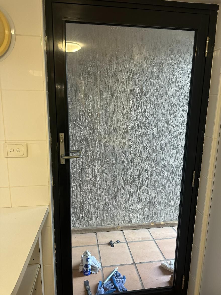 A Black Door Is Open To A Tiled Floor In A Kitchen — Central Coast Glass & Glazing In Kincumber, NSW