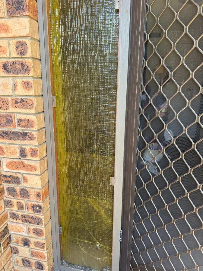 A Brick Wall With A Chain Link Fence And A Broken Glass Door — Central Coast Glass & Glazing In Kincumber, NSW