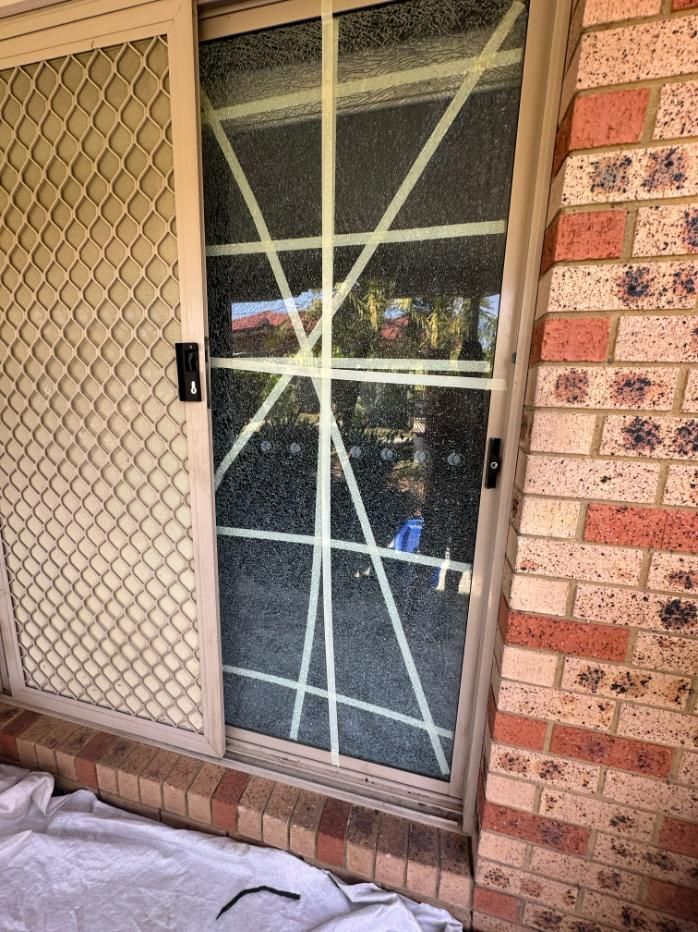 A Sliding Glass Door Is Taped To A Brick Wall — Central Coast Glass & Glazing In Umina Beach, NSW