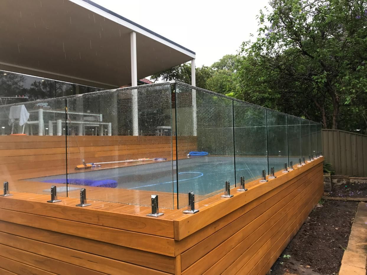 A Swimming Pool With A Glass Fence Around It And A Wooden Deck — Central Coast Glass & Glazing In Umina Beach, NSW