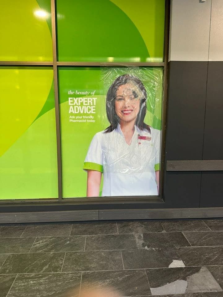 Poster of a Smiling Pharmacist in a White Coat Behind Glass