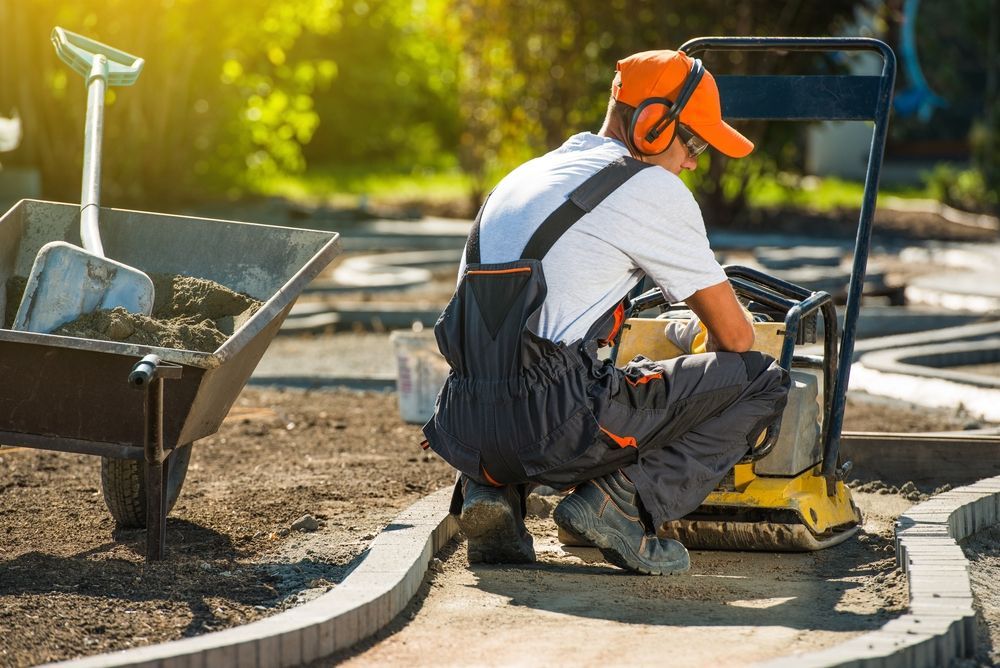 A man wearing headphones is kneeling down next to a machine.