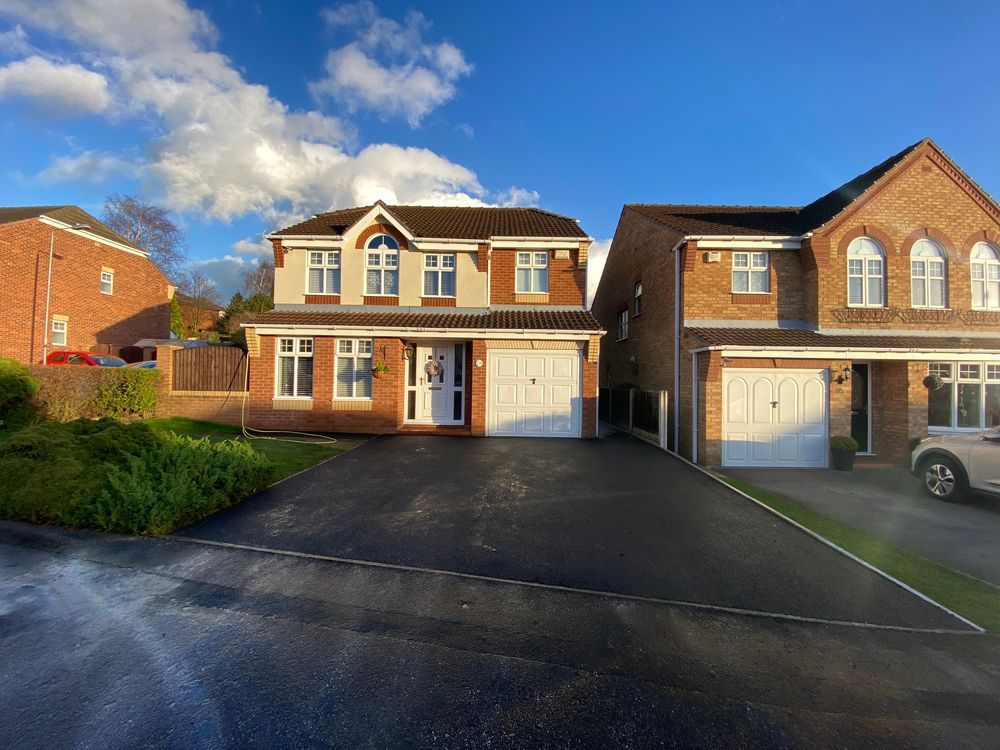 A car is parked in front of a brick house.