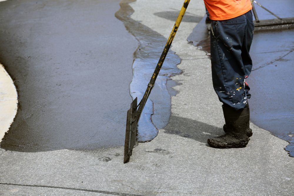 A man is using a shovel to spread asphalt on the ground.