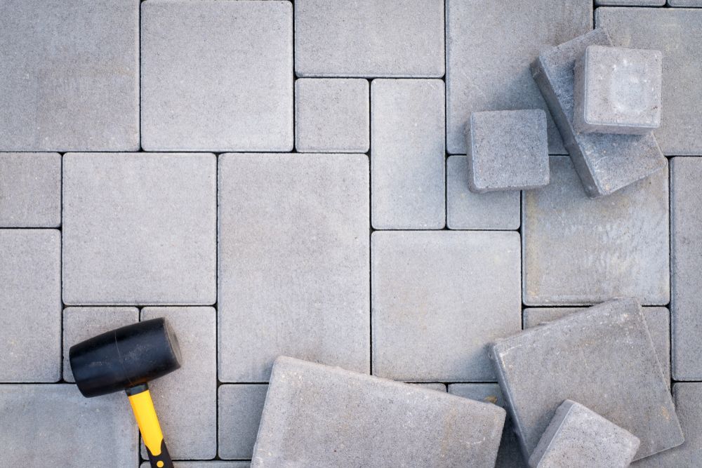 A hammer is laying on top of a pile of concrete tiles.