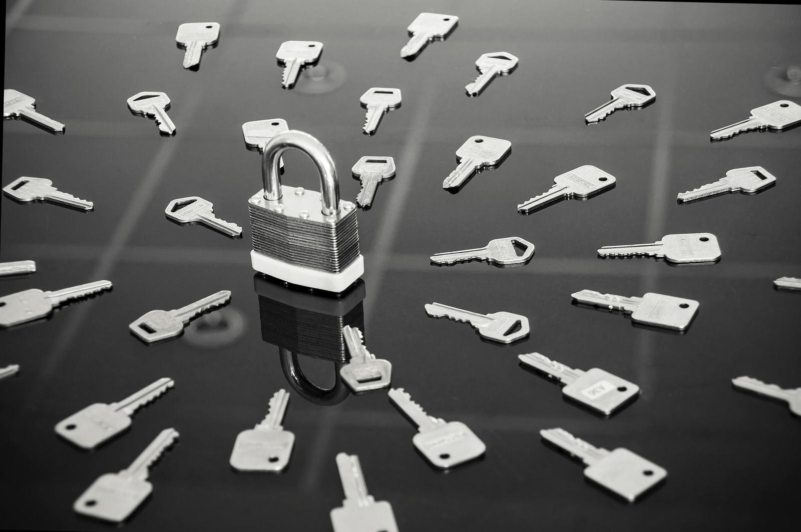 A padlock is surrounded by keys on a table