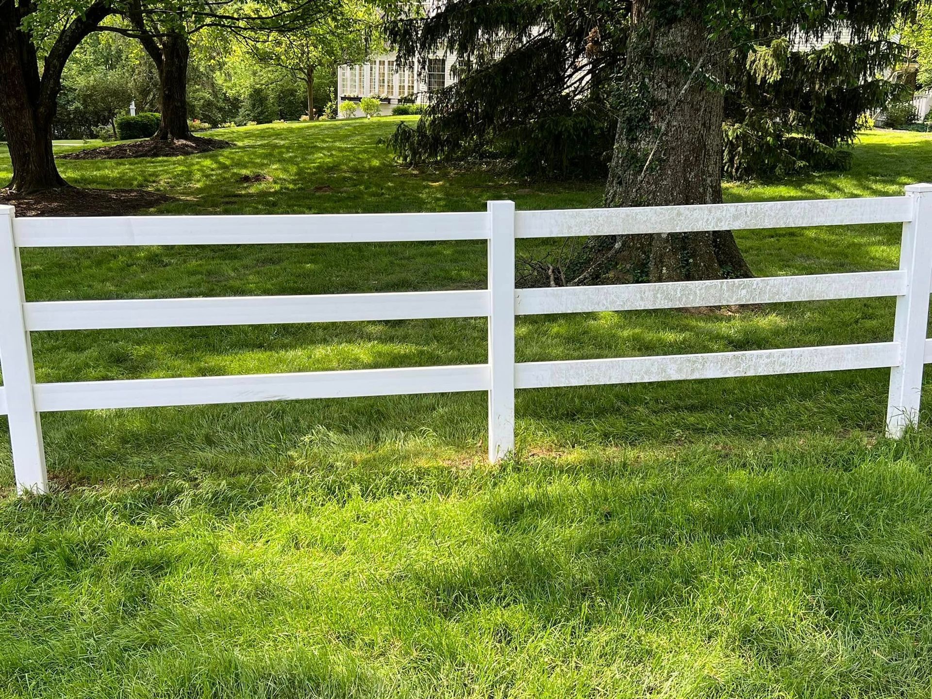 A white fence is sitting in the middle of a lush green field.