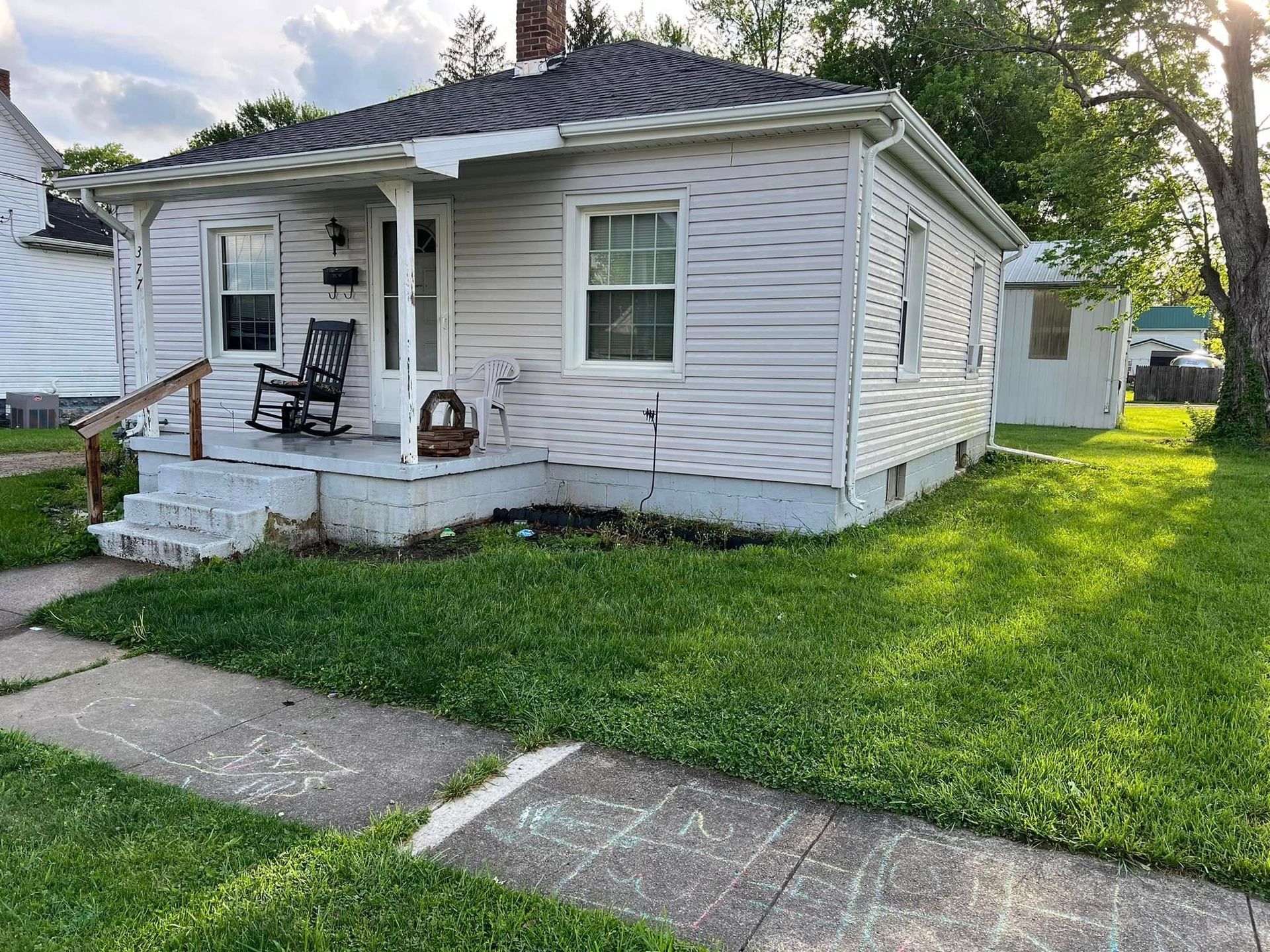 A small white house with a rocking chair on the porch.
