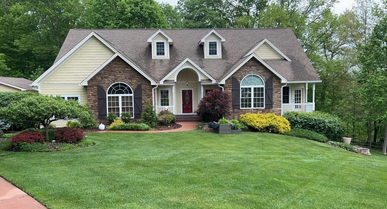 A large brick house with a lush green lawn in front of it.