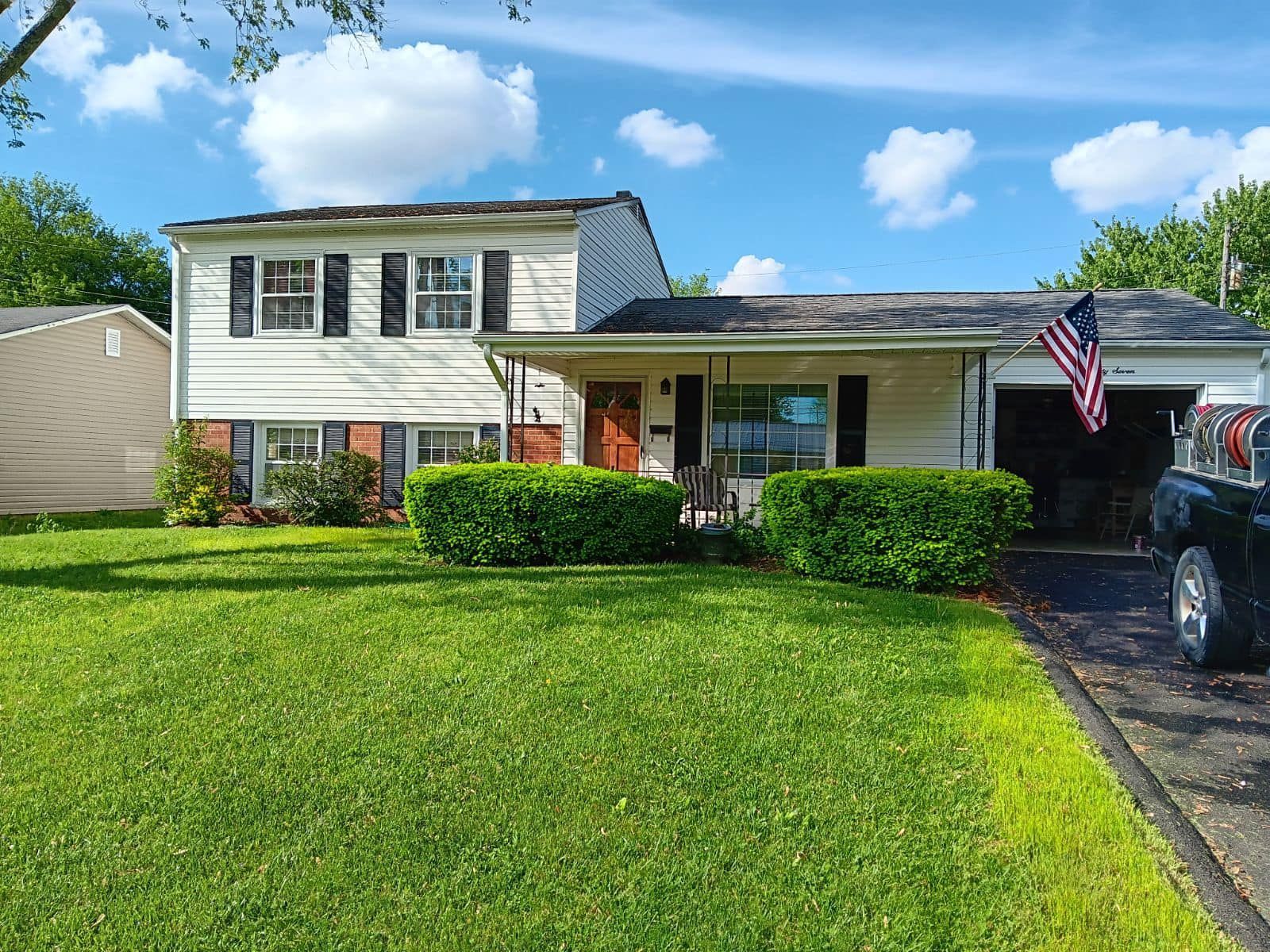 A white house with a black truck parked in front of it.