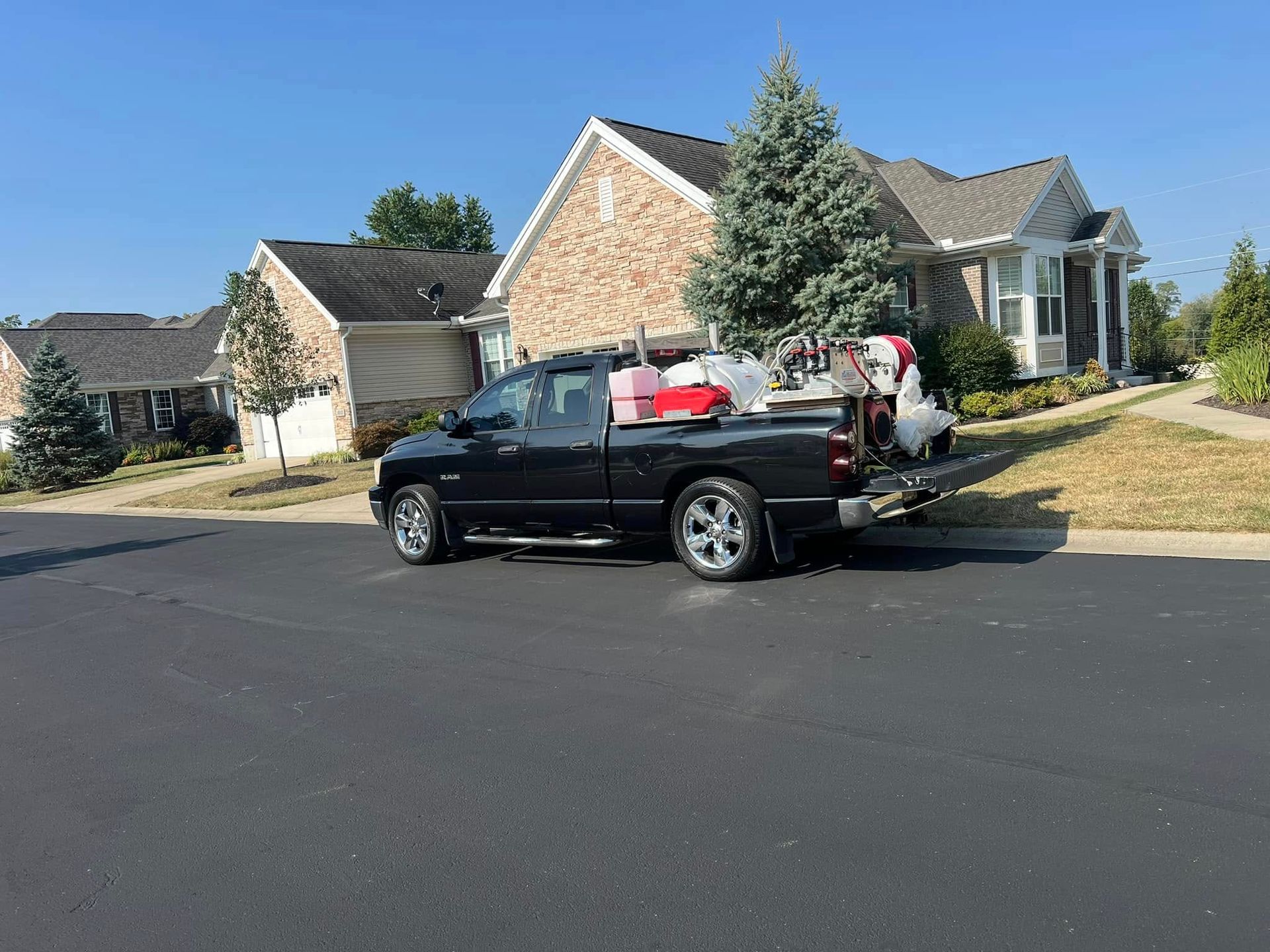 A black truck is parked on the side of the road in front of a house.
