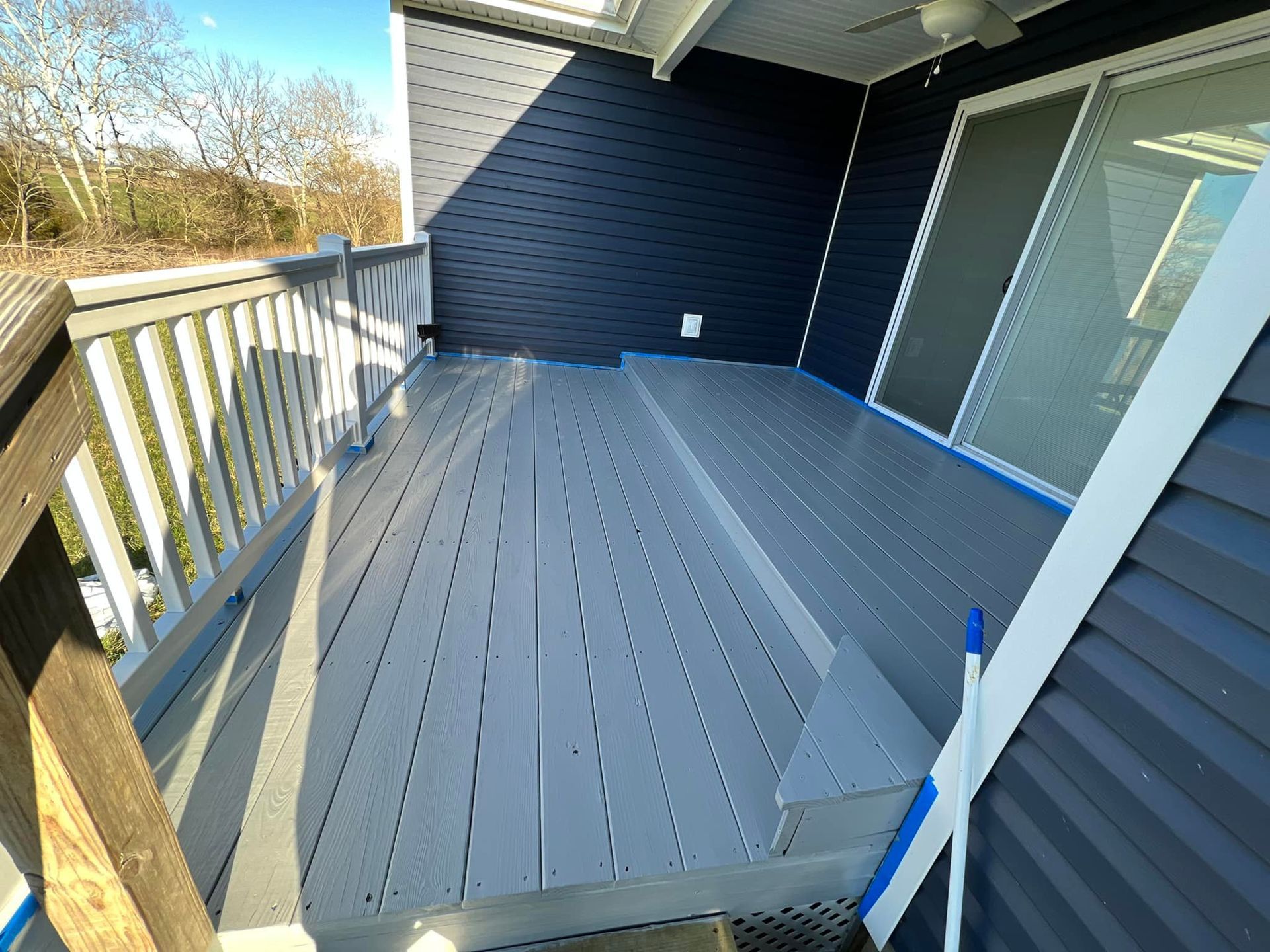 A blue house with a gray deck and stairs