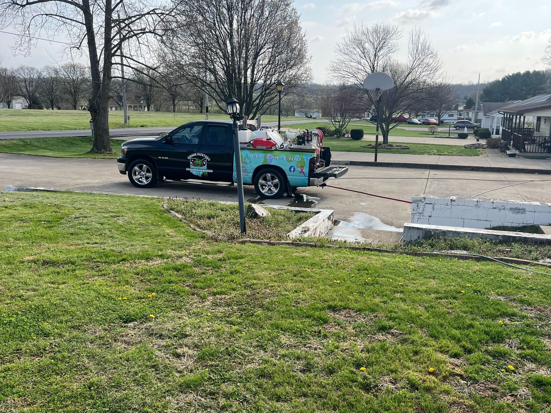 A black pickup truck with a light blue bed parked on a paved driveway in a residential yard.