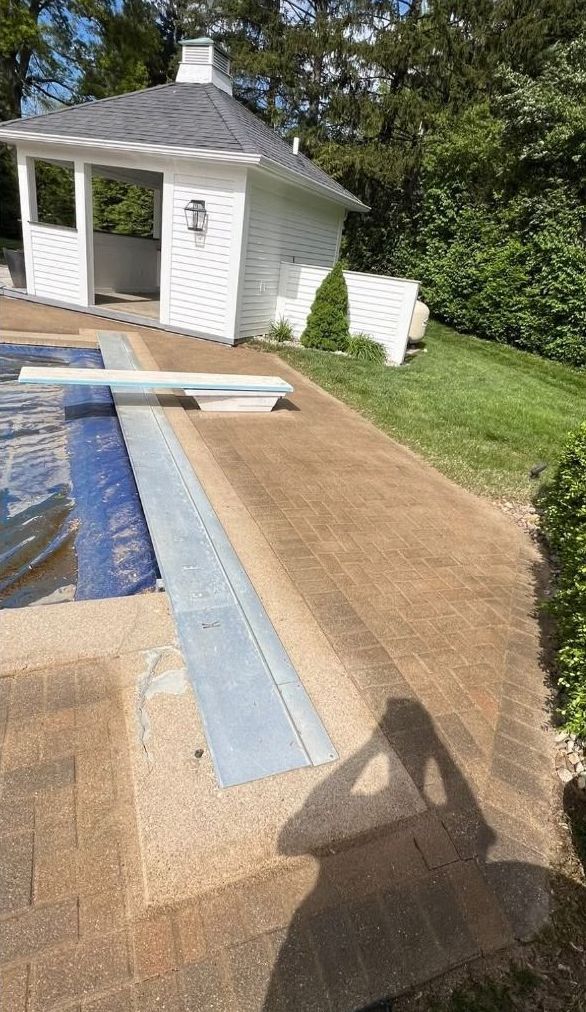 A concrete walkway leading to a house with a fence in the background.