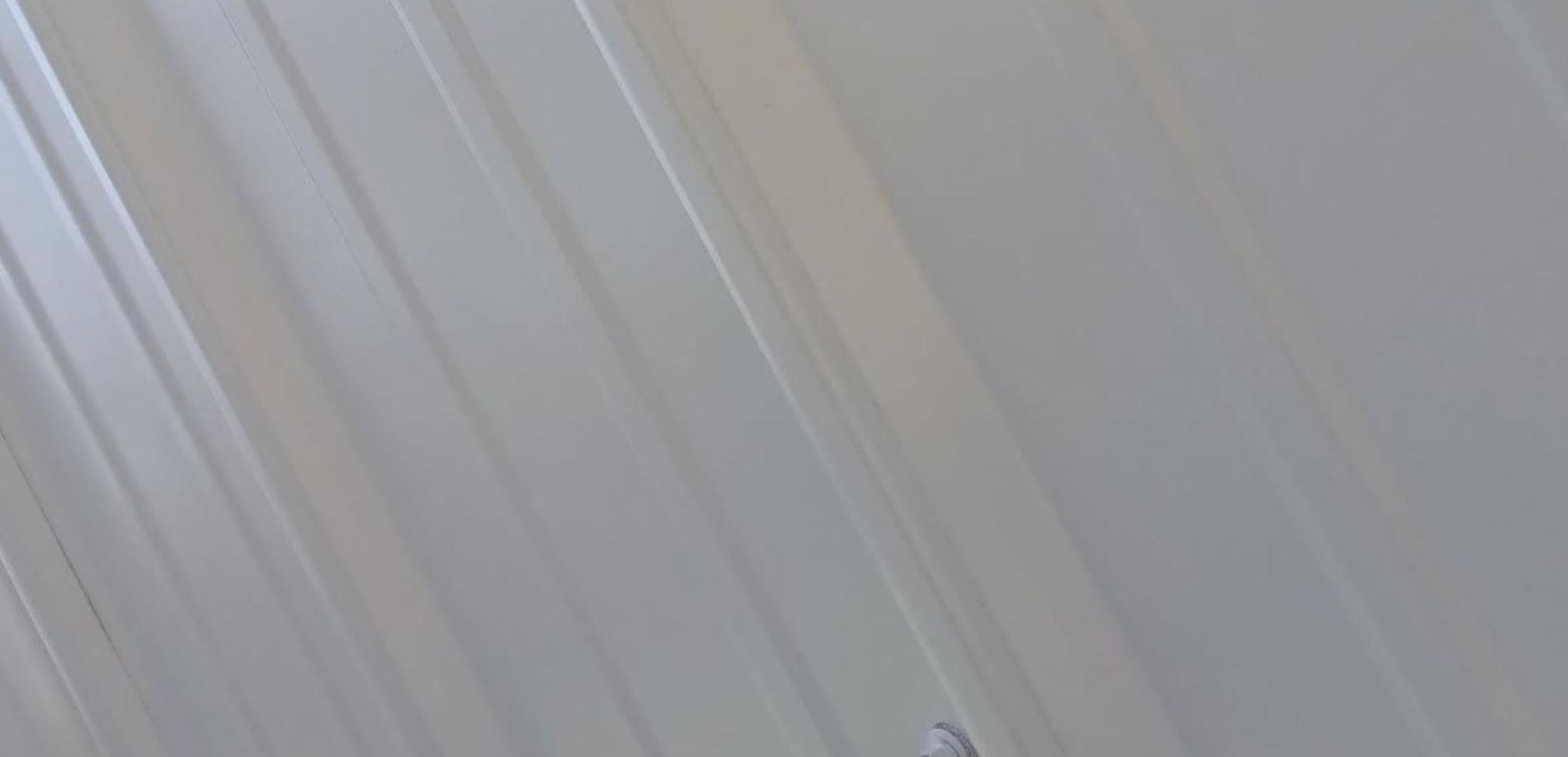 A long porch with a wooden table and a white ceiling.