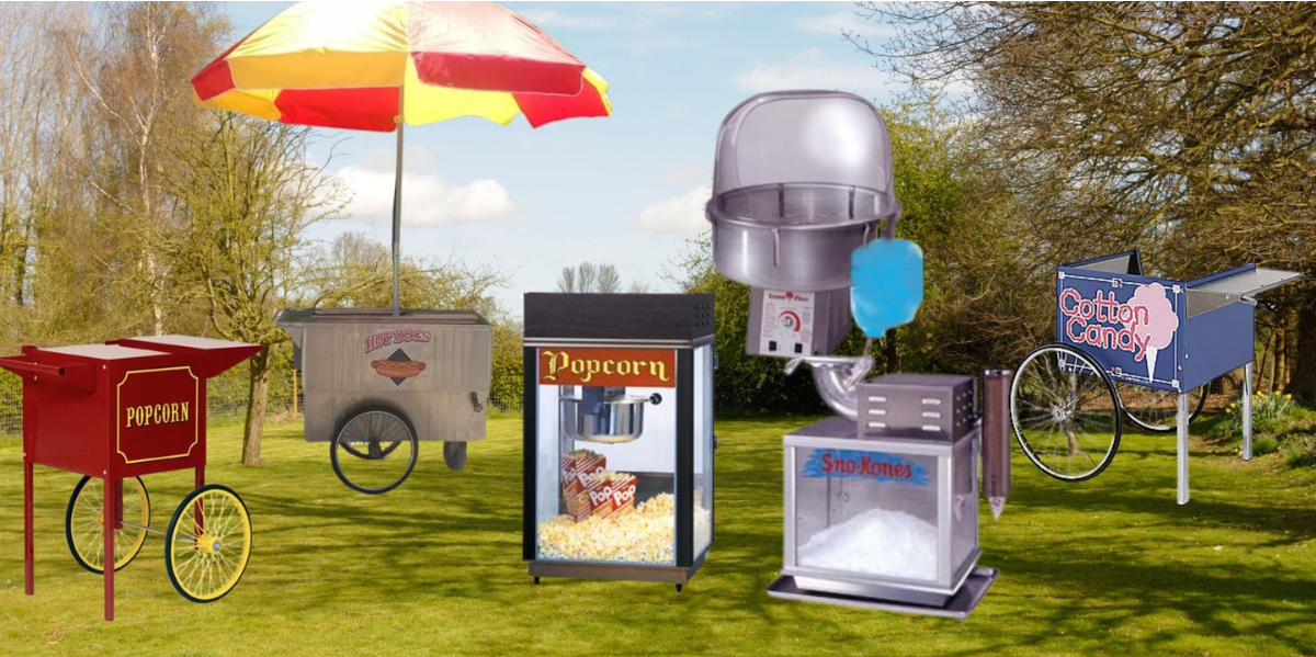 Popcorn and cotton candy machines, including carts and table-top models, arranged on a grassy field.