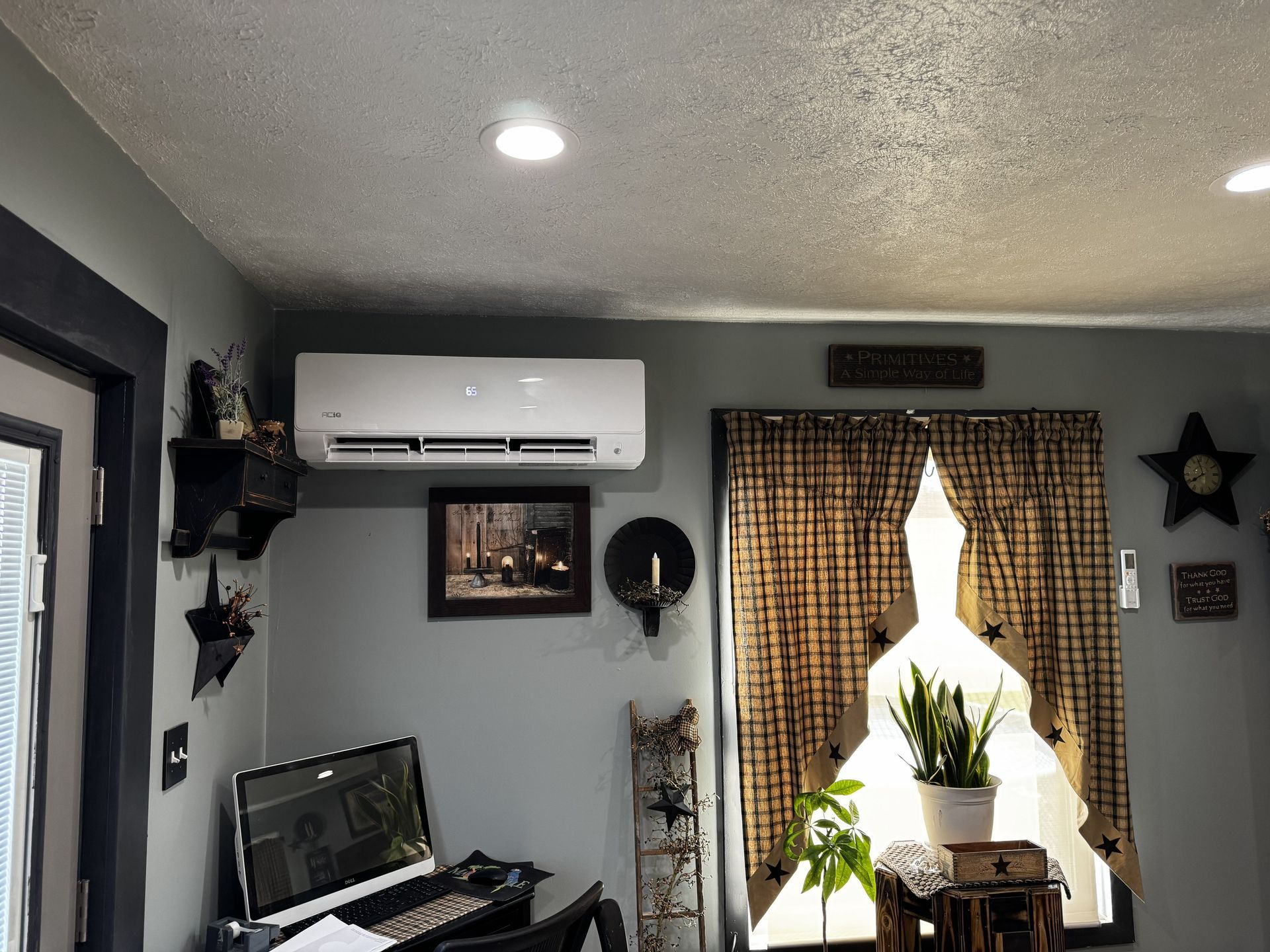 A white wall-mounted air conditioner unit installed on a white wood-paneled wall.