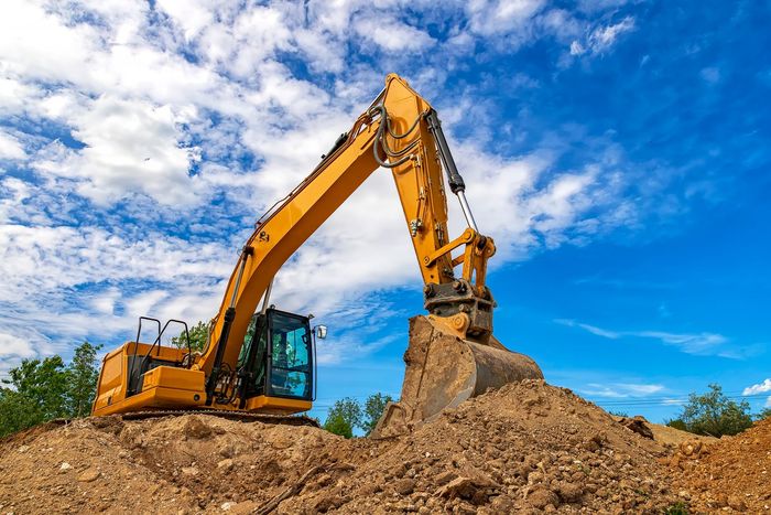 A yellow excavator is working on a pile of dirt. A yellow excavator is working on a pile of dirt.