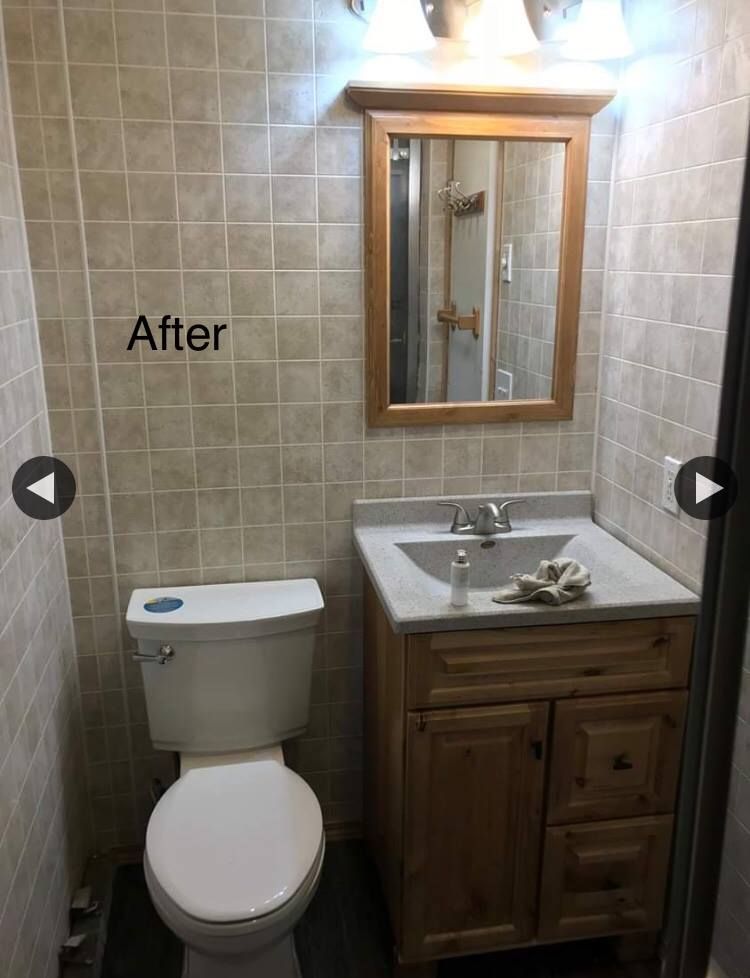 A bathroom with a toilet , sink and mirror.