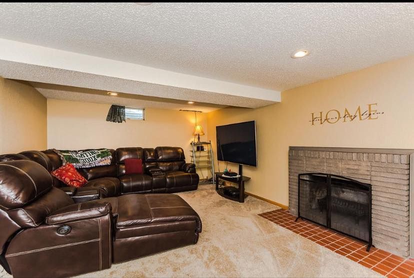 A living room with a large sectional couch and a fireplace.