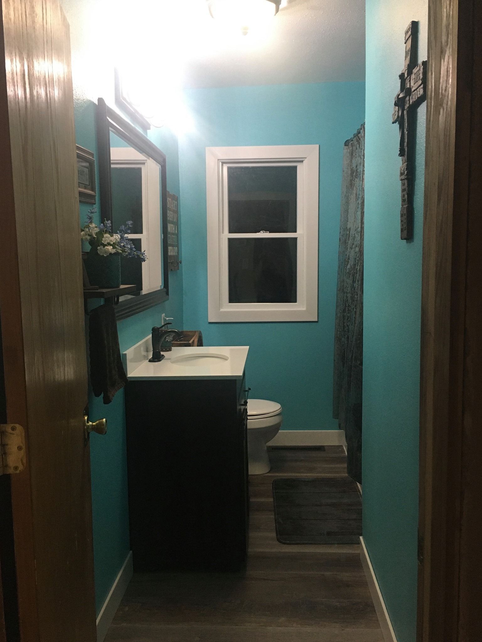 A bathroom with blue walls , a sink , a toilet , and a mirror.