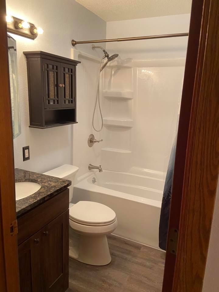 A bathroom with a toilet , sink , bathtub and shower.