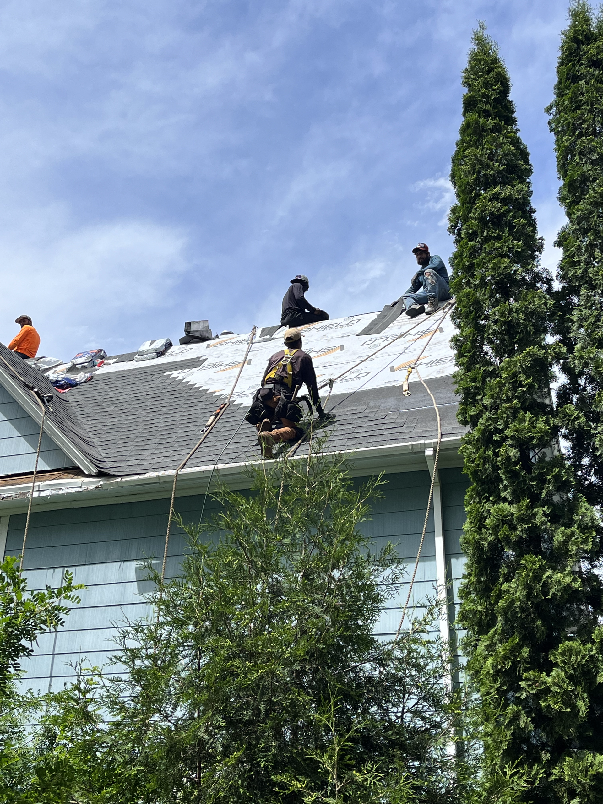 A group of men are working on the roof of a house.